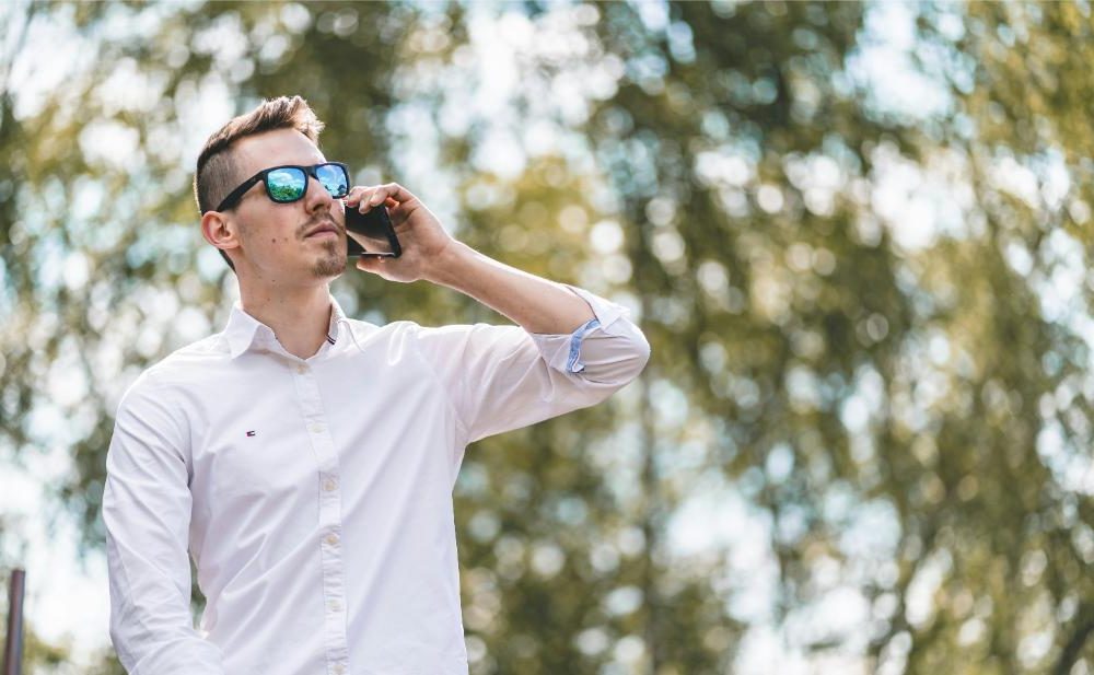 Mann mit Sonnenbrille am Telefon